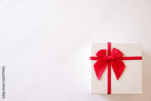 Close-up white gift box with red ribbon on white background.