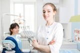 Portrait of a beautiful dentist girl in the clinic on the background of the patient