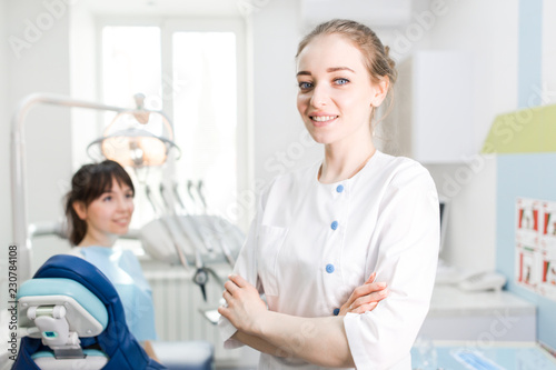 Portrait of a beautiful dentist girl in the clinic on the background of the patient