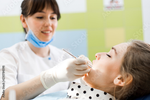 Dentist examines the oral cavity of the patient sitting in the dental chair close-up