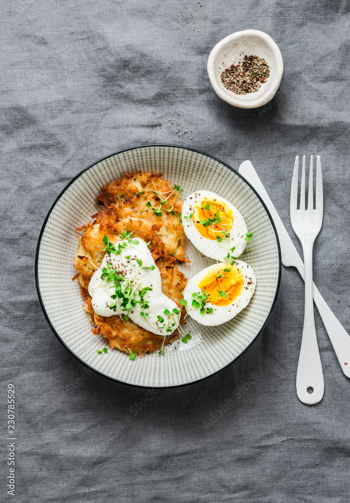 Potato latkes and boiled egg - healthy breakfast or snack on grey background, top view