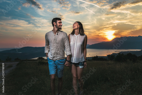 Portrait of young couple having good times in nature behind them is a beautiful sunset over Boka Bay © Mediteraneo