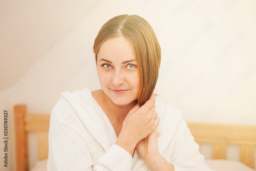Lovely female with wet hair, dries head with towel, being pleased after taking bath, dressed in white bathrobe, poses against white background Lovely female with wet hair, dries head with towel, being pleased after taking bath, dressed in white bathrobe, poses against white background
