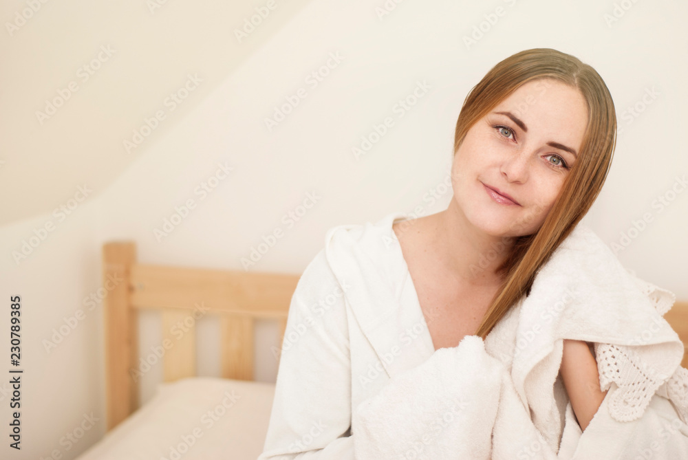 Lovely female with wet hair, dries head with towel, being pleased after taking bath, dressed in white bathrobe, poses against white background Lovely female with wet hair, dries head with towel, being pleased after taking bath, dressed in white bathrobe, poses against white background