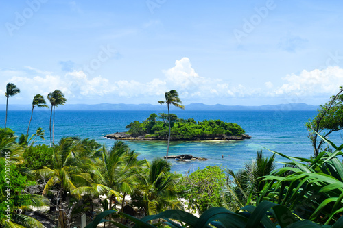 View over island in caribbean sea with many palms  blue sky  some clouds on the horizon  tropical island