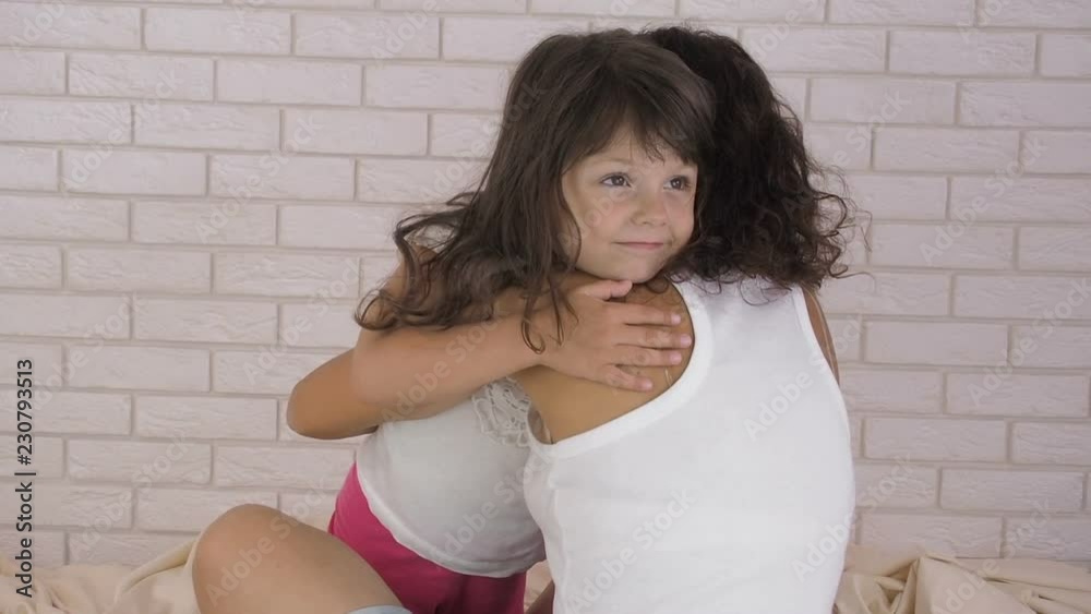 The child hugs the mother. Happy little girl hugs mother in bedroom. The child hugs the mother. Happy little girl hugs mother in bedroom.