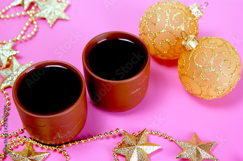 Two cups of tea  golden stars and two shiny glass balls for Christmas decoration on the pink background. Christmas and New Year holiday background concept. Copy space for text.
