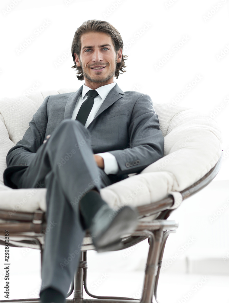 handsome businessman sitting in a large cozy armchair. handsome businessman sitting in a large cozy armchair.