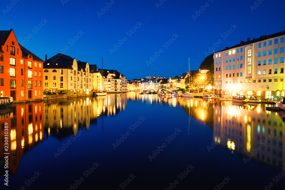 View of center of Alesund, Norway at night with reflection in the river