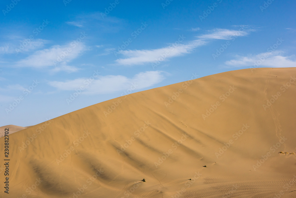 Desert sand dunes with blue sky background. Beautiful curves of deserts