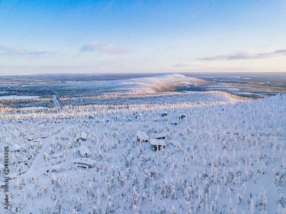 Aerial view of winter forest with frosty trees, rural road and village in Finland Aerial view of winter forest with frosty trees, rural road and village in Finland