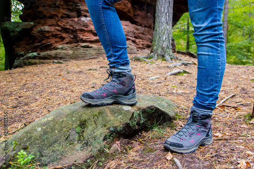 Hiking shoes of a young woman in the forest wearing jeans, ready for active outdoor adventures. Selective focus