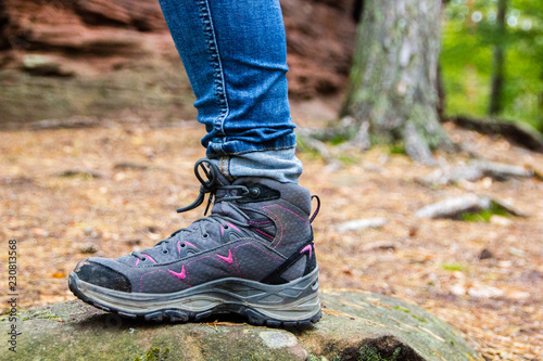 Hiking shoes of a young woman in the forest wearing jeans, ready for active outdoor adventures. Selective focus