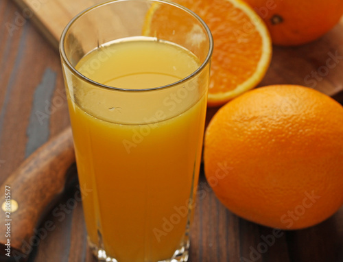 Oranges and a glass of orange juice on a wooden table.