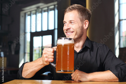Spotkanie przy piwie. Uśmiechnięty przystojny mężczyzna z kuflem piwa pszenicznego. 