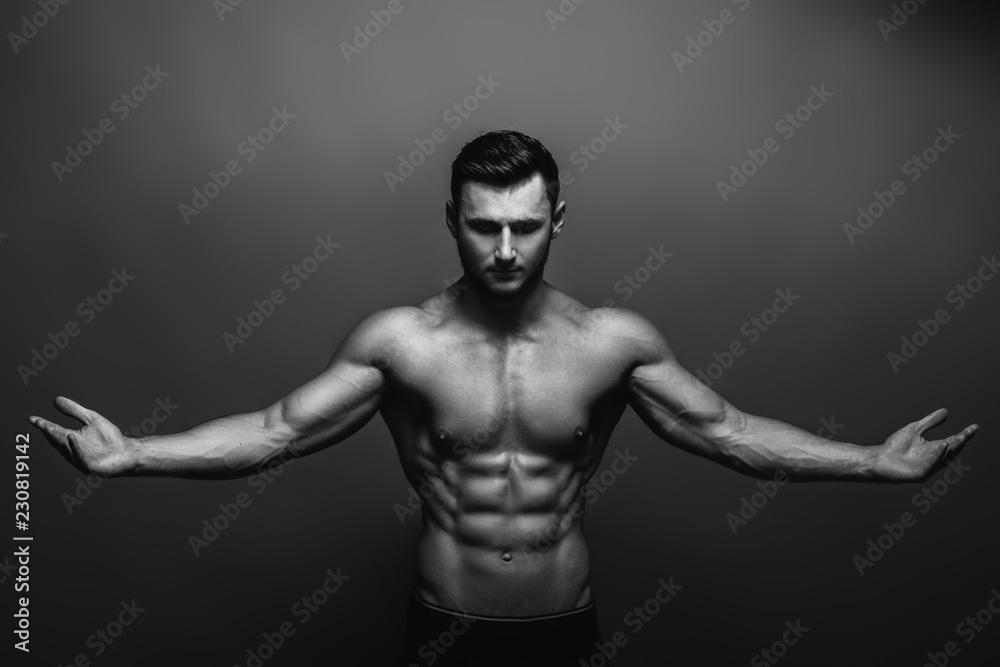 Fototapeta premium Bodybuilding. Strong man posing on background. Athletic young boy showing muscles.