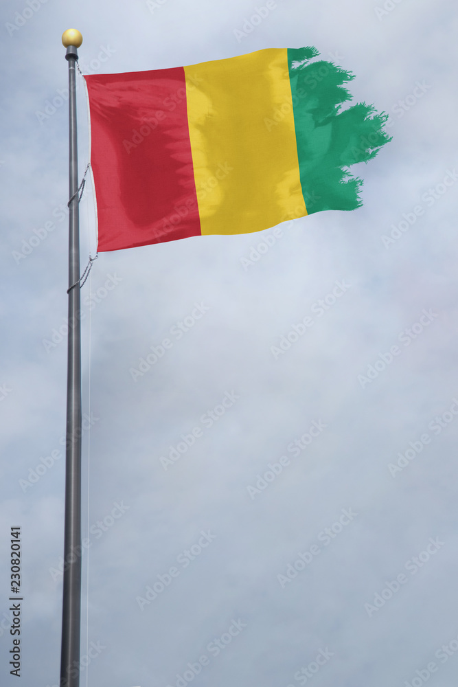Worn and tattered Guinea flag blowing in the wind on a cloudy day Worn and tattered Guinea flag blowing in the wind on a cloudy day