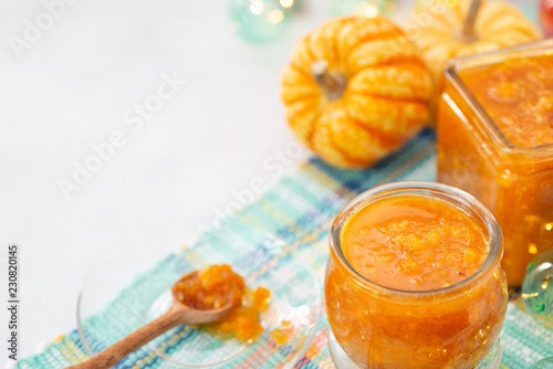 Pumpkin jam or confiture on a cozy kitchen table. Autumn background with copy space. Selective focus.