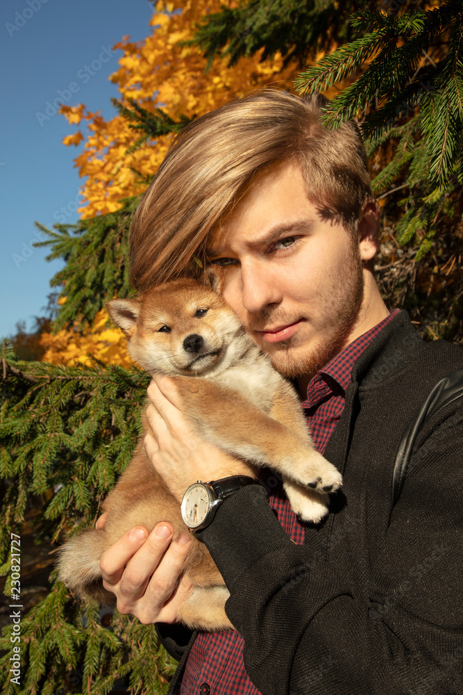 Young smiling young man hugging his little puppy Young smiling young man hugging his little puppy