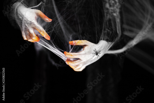 Creepy halloween hands with red, orange and silver covered in a spider web with spiders, black lace gothic dress, can be used as background