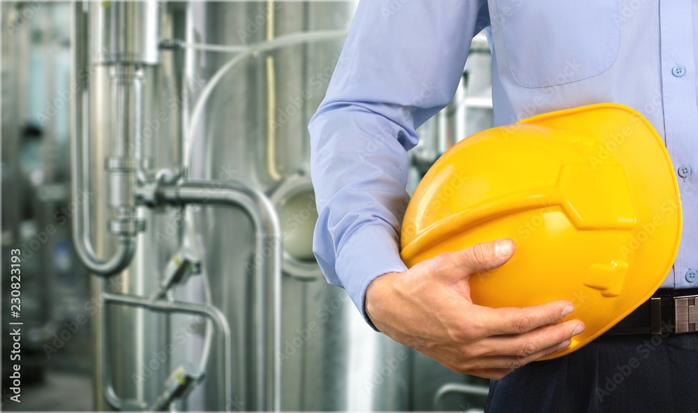 Unrecognizable businessman holding in hand yellow helmet Unrecognizable businessman holding in hand yellow helmet