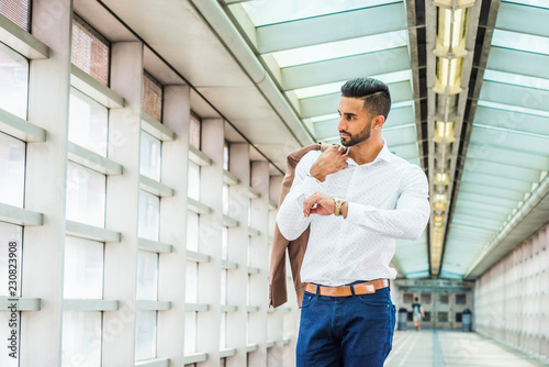 Young East Indian American Businessman with beard in New York, wearing white shirt, carrying jacket over shoulder, standing inside indoor walkway, raising arm with wristwatch, looking away, thinking.. Free Download Young East Indian American Businessman with beard in New York, wearing white shirt, carrying jacket over shoulder, standing inside indoor walkway, raising arm with wristwatch, looking away, thinking.. - GFXLoad