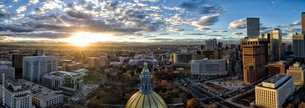 Aerial/Drone panorama of the capital city of Denver, Colorado at sunset. The Rocky Mountains can be seen on the horizon