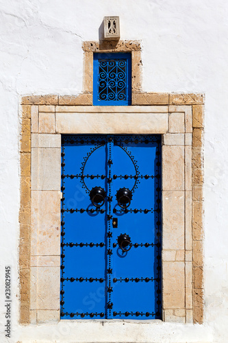 Blue door with sand color, yellow brick door post and a white wall at the blue and white houses of Sidi Bou Said in Tunisia.