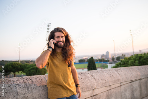 young man with long hair using his mobile phone © marc