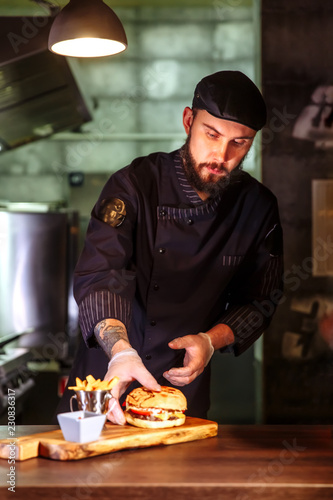 Chef putting bun on top,he making a beef burger for customer order.