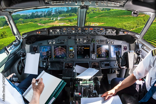 Airplane cockpit flying on grapevine of Constantia Valley, Cape Town in South Africa, with pilots arms and blank white papers for copy space.