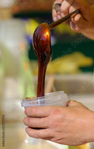 Beekeeper pours honey into the container on the market