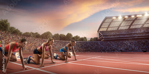 Female athletes sprinting. Three women in sport clothes on starting line prepares to run at the running track in professional stadium