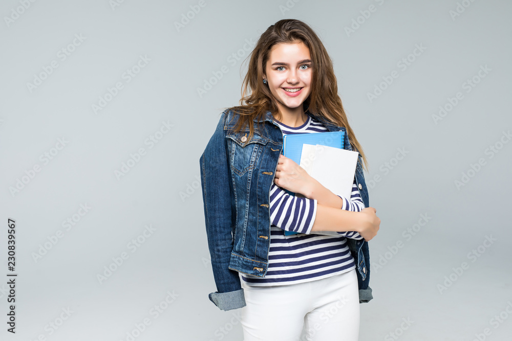Confident smiling stylish teenage girl dressed in leather jacket, with a backpack on her shoulder is going to the high school isolated on grey background Confident smiling stylish teenage girl dressed in leather jacket, with a backpack on her shoulder is going to the high school isolated on grey background