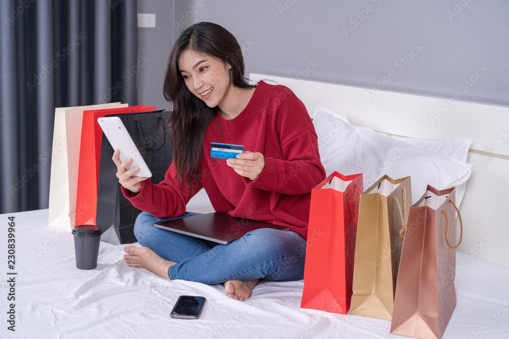 happy woman using tablet for online shopping with credit card on bed happy woman using tablet for online shopping with credit card on bed