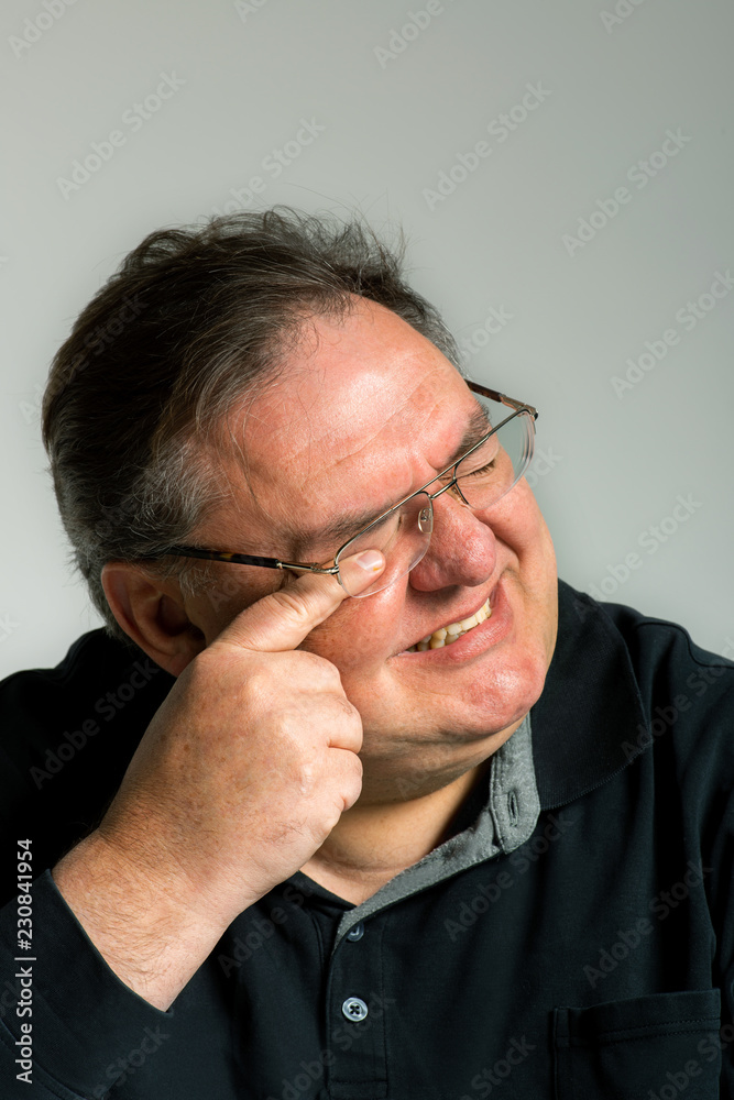 Fototapeta premium müder Mann mit Brille reibt sich die erschöpften Augen mit verzerrtem Gesicht