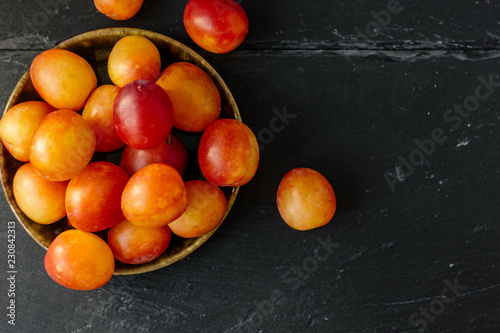 Top view of wild plums fruits on black stone background.