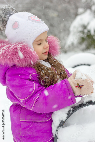 Little kid girl playing snowballs on winter morning.