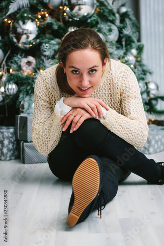 Portrait of young girl sitting near the christmas tree.