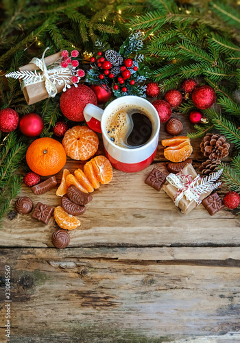 Christmas holiday card. beautiful cozy composition with Christmas decor, cones, treats, tangerines, chocolate and coffee cup on wooden table. festive winter season. Top View. copy space