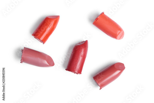 top view of cut lipsticks on different colors on white backdrop