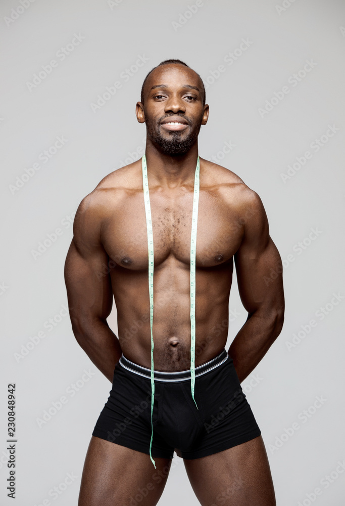 Black man, fitness and body, measuring tape and abs with health