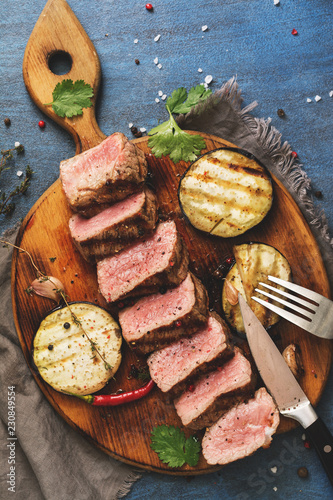 Grilled beef steak medium rare on wooden cutting board,blue rustic background. Top view,overhead