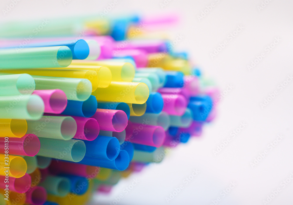 Close up on multiple plastic straws laying on a white background Close up on multiple plastic straws laying on a white background