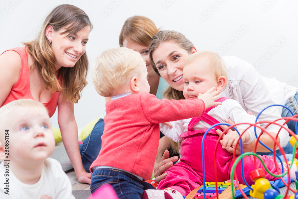 Group of happy young mothers watching their cute and healthy babies Group of happy young mothers watching their cute and healthy babies