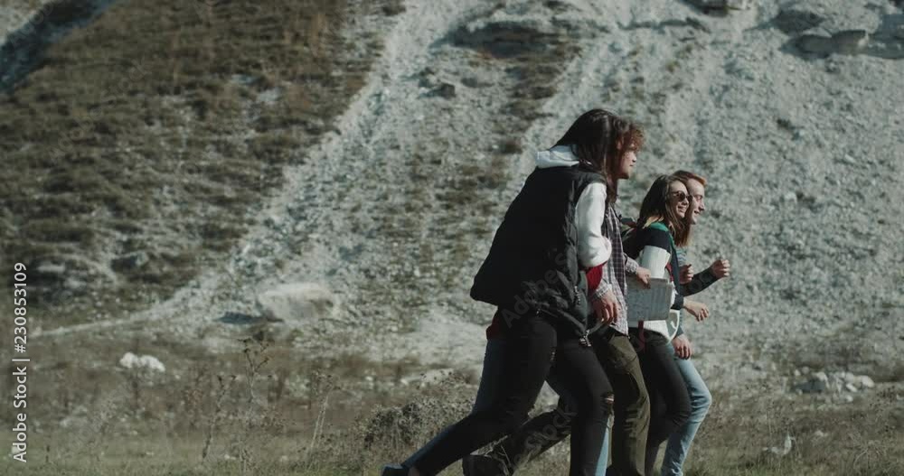 Good time for five friends , in the mountain trip , walking through the field happy and smiling holding in their back a big trip bags. Good time for five friends , in the mountain trip , walking through the field happy and smiling holding in their back a big trip bags.