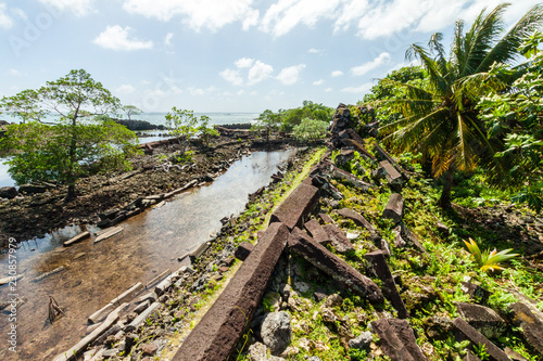 Fotografija Walls and canals of Nandowas part of Nan Madol - overgrown prehistoric ruined stone city, palms