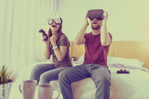 Virtual reality. Young nice couple using virtual reality glasses spending time together at home