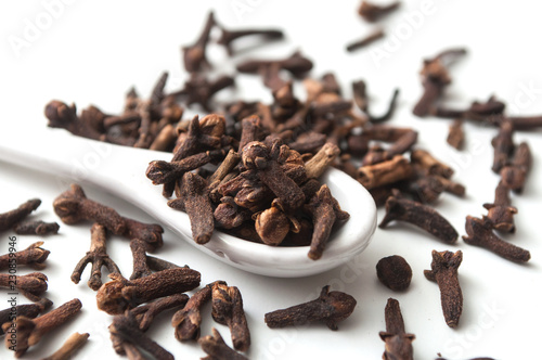 closeup of cloves in white spoon on white background