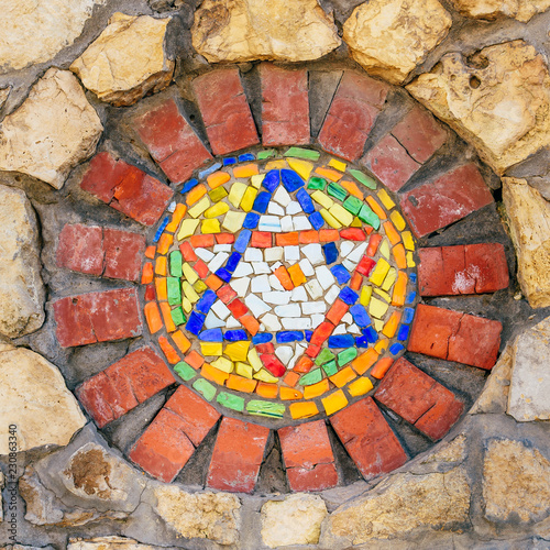 Mosaic star of David on stone wall. © seva_blsv